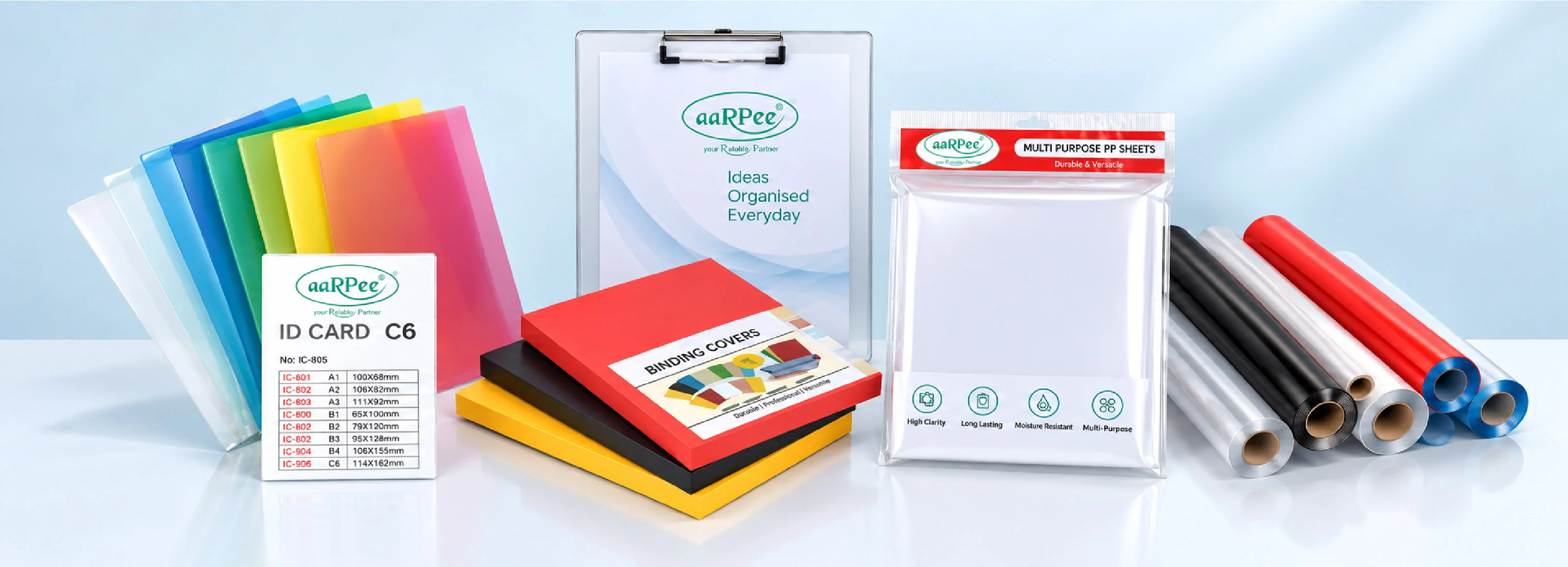 Aarpee L folders in six colours, a clipboard, binding covers, a pack of multi-purpose PP sheets, and rolls of book-covering film on a pale blue surface
